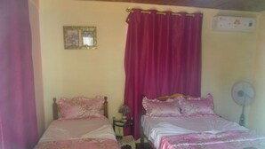 A bedroom with two beds, each with pink bedding and floral patterns. There is a small table with a lamp between the beds, and a wall-mounted air conditioner above the right bed. - Casa Yaquelin y Osmani (Viñales)