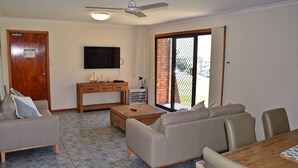 Ein Wohnzimmer mit einer Couch, einem Couchtisch, einem Fernseher und einer Glastür zum Patio.