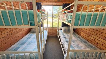 A bunk bed room with a brick wall and a window.
