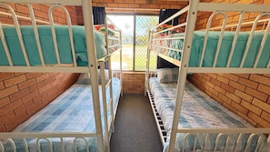 Quarto com beliche, parede de tijolos e janela.