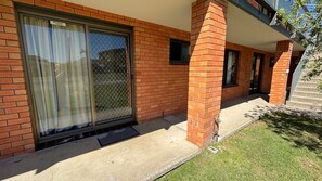 A residential building with a brick facade, a sliding glass door, and a small window.