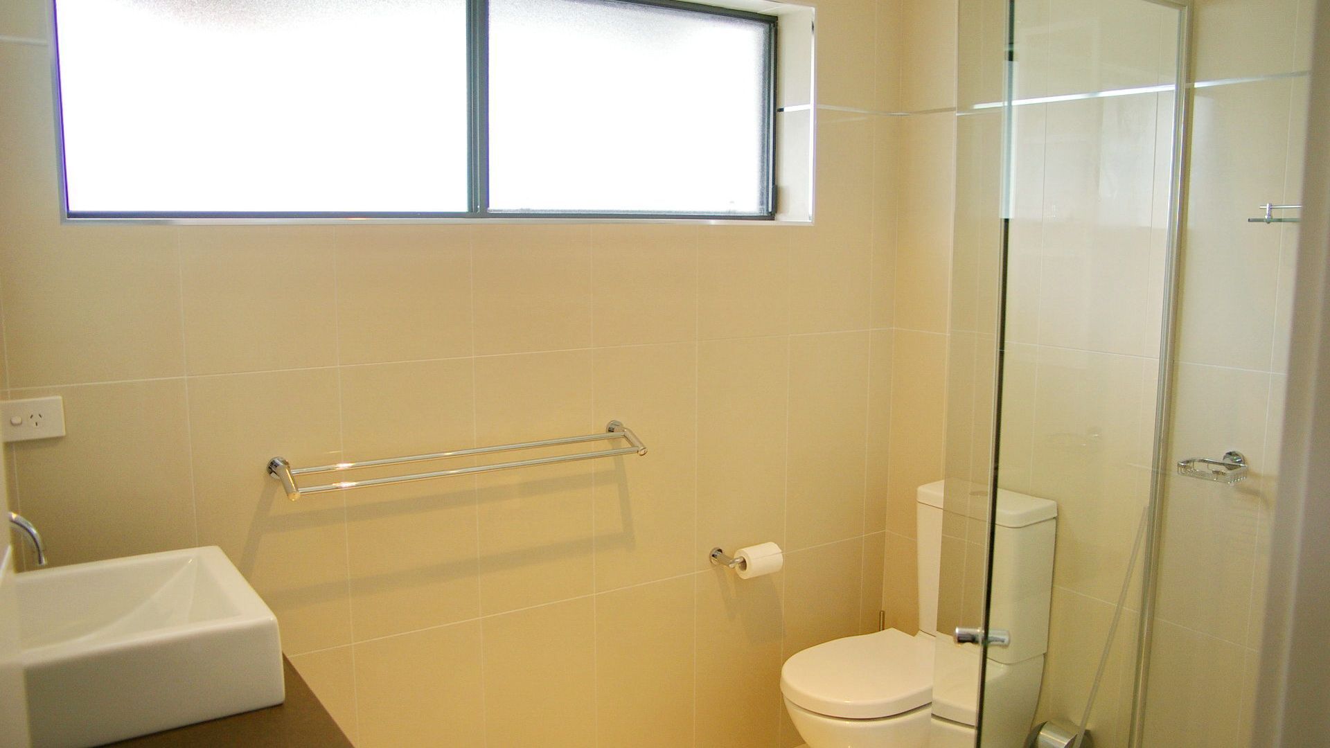 Une salle de bain comprenant des toilettes, une douche à parois de verre et un lavabo.