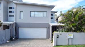 A modern two-story building with a white garage door, a small balcony, and a sign indicating holiday letting. - Cool & Calm - walk to the beach (SOUTH WEST ROCKS)