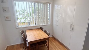 A room with a wooden table, chairs, a window with blinds, and white cabinets. - Mountain View Hat Head - Bring your own linen (HAT HEAD)