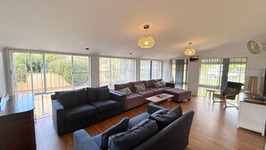A spacious living area with a large sofa set, a coffee table, and a dining area with a chair and table. - Mountain View Hat Head - Bring your own linen (HAT HEAD)