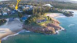 An aerial view of a coastal property with a beach, a small island with a house, and a lighthouse in the distance. - Paragon Apartment 3 - walk to the beach (South West Rocks)