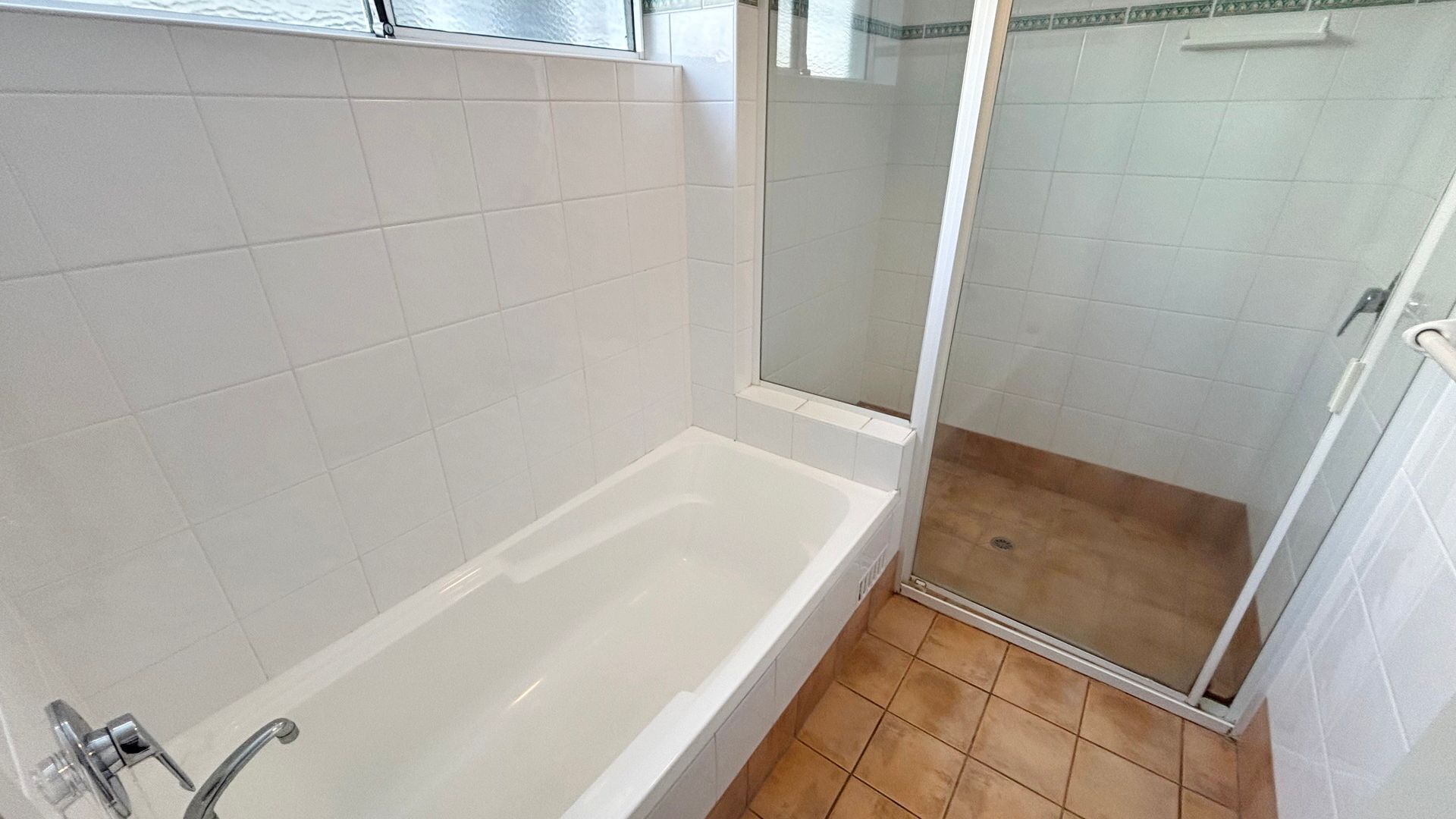 Une salle de bain avec une baignoire, une douche et un carrelage au sol.