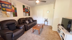 A living room with a sofa, a coffee table, a television, and wall art. - Seldom Inn  - close to the water (SOUTH WEST ROCKS)