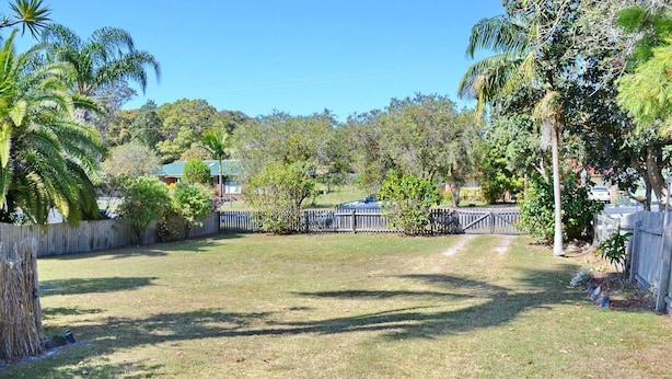 A fenced backyard with a lawn, trees, and a house in the background. - Seldom Inn  - close to the water (SOUTH WEST ROCKS)