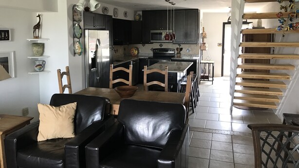 A modern kitchen with dark cabinets, a stainless steel refrigerator, and a central island. - Fenwick Paradise Beach Villa-Beautiful Bayfront Condo .9Miles From The Beach<br> (Selbyville)