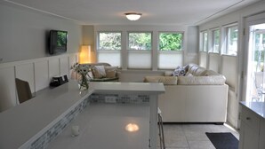 Una cocina moderna con encimera blanca, estufa integrada y comedor con sofá blanco.
