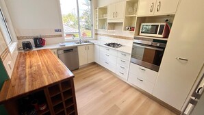 Une cuisine dotée d’un plan de travail en bois, de meubles blancs, d’une cuisinière à gaz, d’un four et d’un four à micro-ondes.