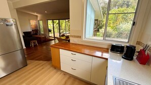 Une cuisine avec un plan de travail en bois, un réfrigérateur et une fenêtre donnant sur un paysage verdoyant.