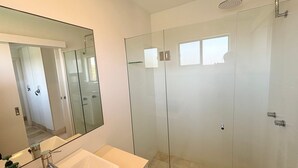 A modern bathroom with a glass shower enclosure, a large mirror, and a white sink. - Seacrest Unit 4 - walk to the beach - Bring your own linen (South West Rocks)