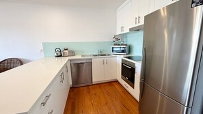 Eine moderne Küche mit weißen Schränken, Edelstahlgeräten und Holzboden.