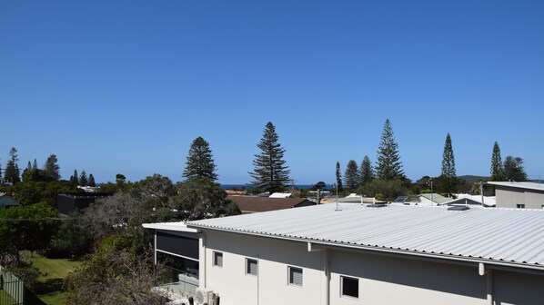 A modern building with a flat roof, surrounded by trees and a clear blue sky.