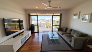 A modern living room with a flat-screen TV, a sofa, a coffee table, and a ceiling fan.