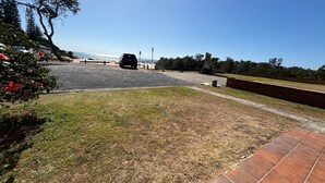 A paved driveway leading to a building with a clear view of the ocean.