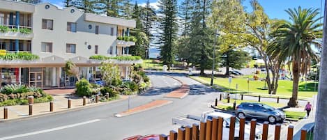 A hotel with a modern design, featuring a large entrance, a covered patio area, and a parking lot with several cars.