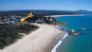 An aerial view of a coastal area with a beach, ocean, and a cluster of buildings. - Waterford Apartment 5 (South West Rocks)
