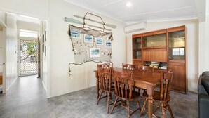 A dining area with a wooden table and chairs, a wall-mounted photo display, and a wooden cabinet with glass doors.