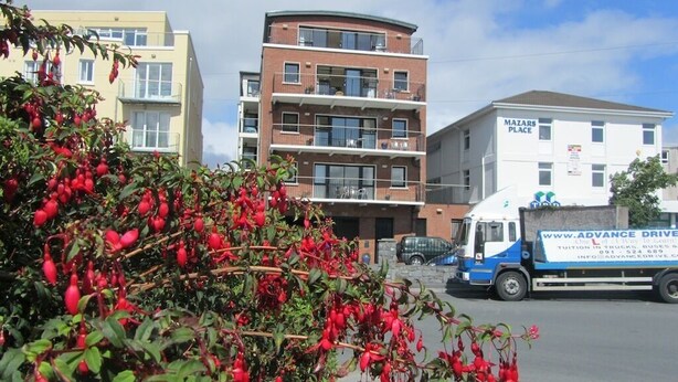 A multi-story building with balconies, a truck with 'Advance Drive' branding, and a sign for 'Mazars Place'. - Sea View Apartment   situated on the seafront near the village Salthill (Galway)