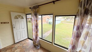 Ein Zimmer mit Tür, Fenster und Blick auf einen Garten.