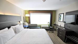 Une chambre d’hôtel avec un grand lit, un bureau équipé d’un ordinateur, une chaise et un téléviseur.