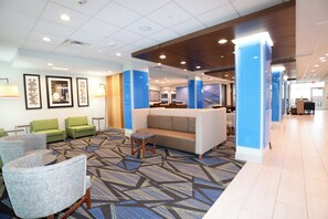 A hotel lobby with seating areas, a reception desk, and a patterned carpet.
