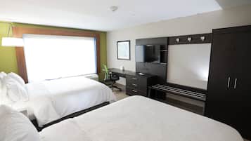 Ein Hotelzimmer mit zwei Betten, einem Schreibtisch, einem Fernseher und einem Kleiderschrank.