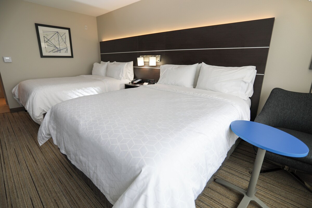Ein Hotelzimmer mit zwei Betten, einem Nachttisch, einem Schreibtisch und einem Stuhl.