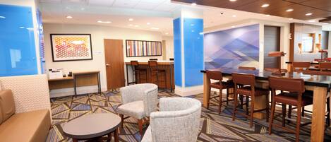 A hotel lobby with a seating area, a reception desk, and a bar.