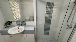 A bathroom with a sink, mirror, and shower. - Jubilee Apartment 03 - Bring your own linen (South West Rocks)