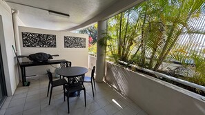 Een balkon met een tafel, stoelen, een laptop en decoratieve panelen.