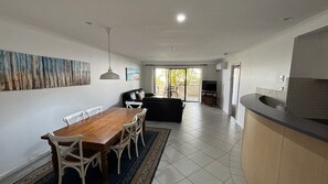 Een moderne keuken met een eethoek, een woonkamer met een bank en een televisie.