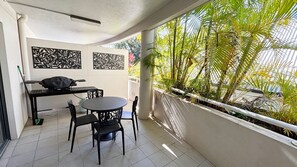 A balcony with a dining table and chairs, a laptop, and decorative panels.