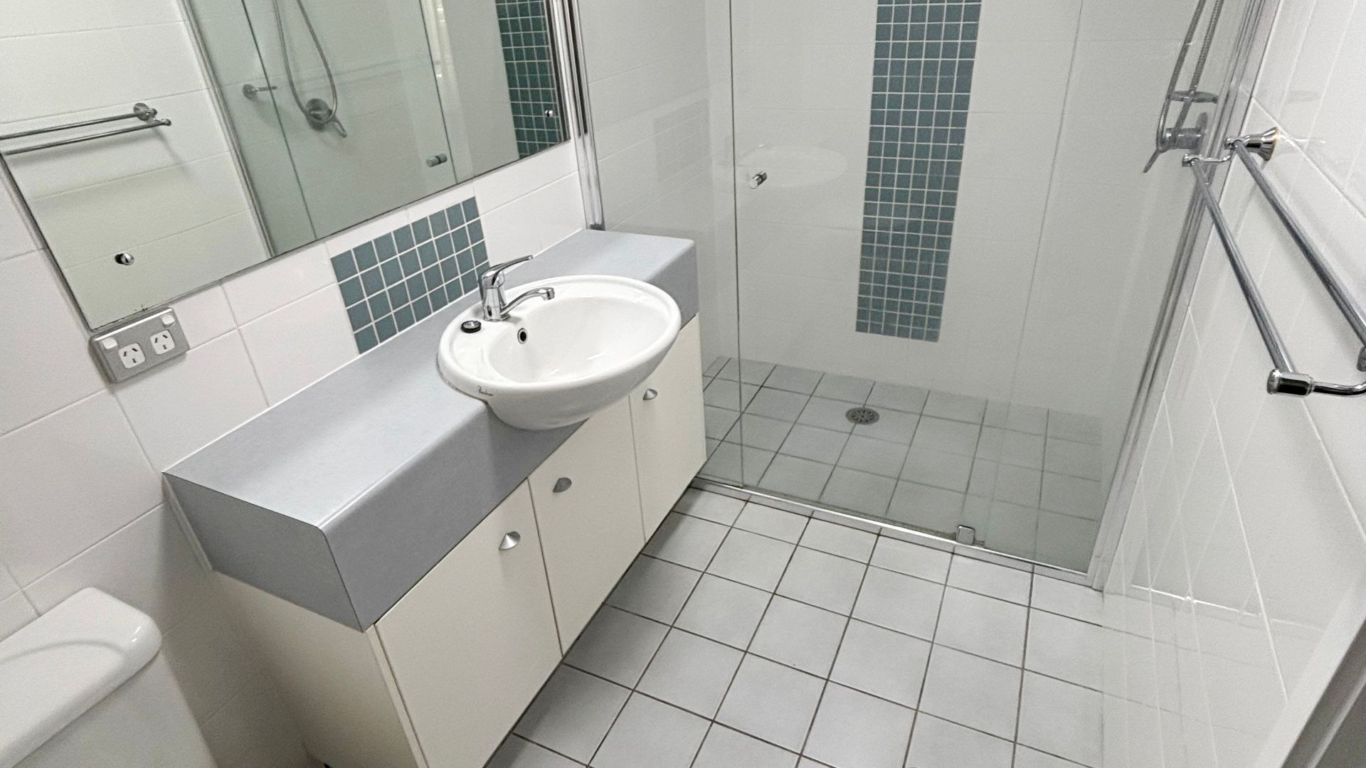 Un baño con lavamanos, espejo y ducha.