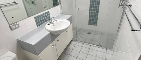 Un baño con lavamanos, espejo y ducha.