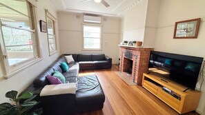 A living room with a sectional sofa, a fireplace, and a television on a wooden stand.