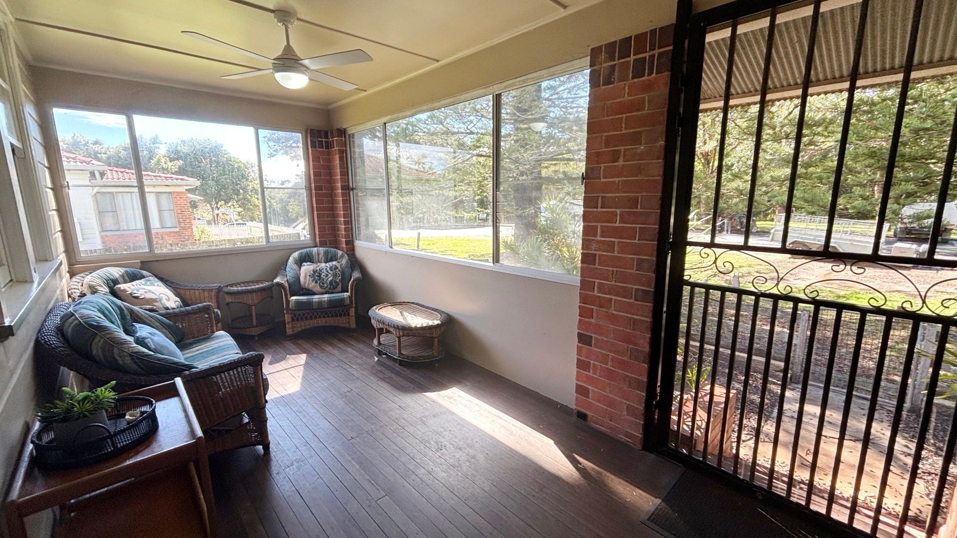 A sunroom with a ceiling fan, wicker furniture, and large windows offering a view of the outdoors.