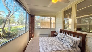 A bedroom with a bed, a window, and a ceiling fan. - Yia Yia's Place - walk to the beach - Bring your own linen (SOUTH WEST ROCKS)