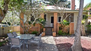 A house with a brick exterior, a front porch, and a backyard with a table and chairs. - Yia Yia's Place - walk to the beach - Bring your own linen (SOUTH WEST ROCKS)