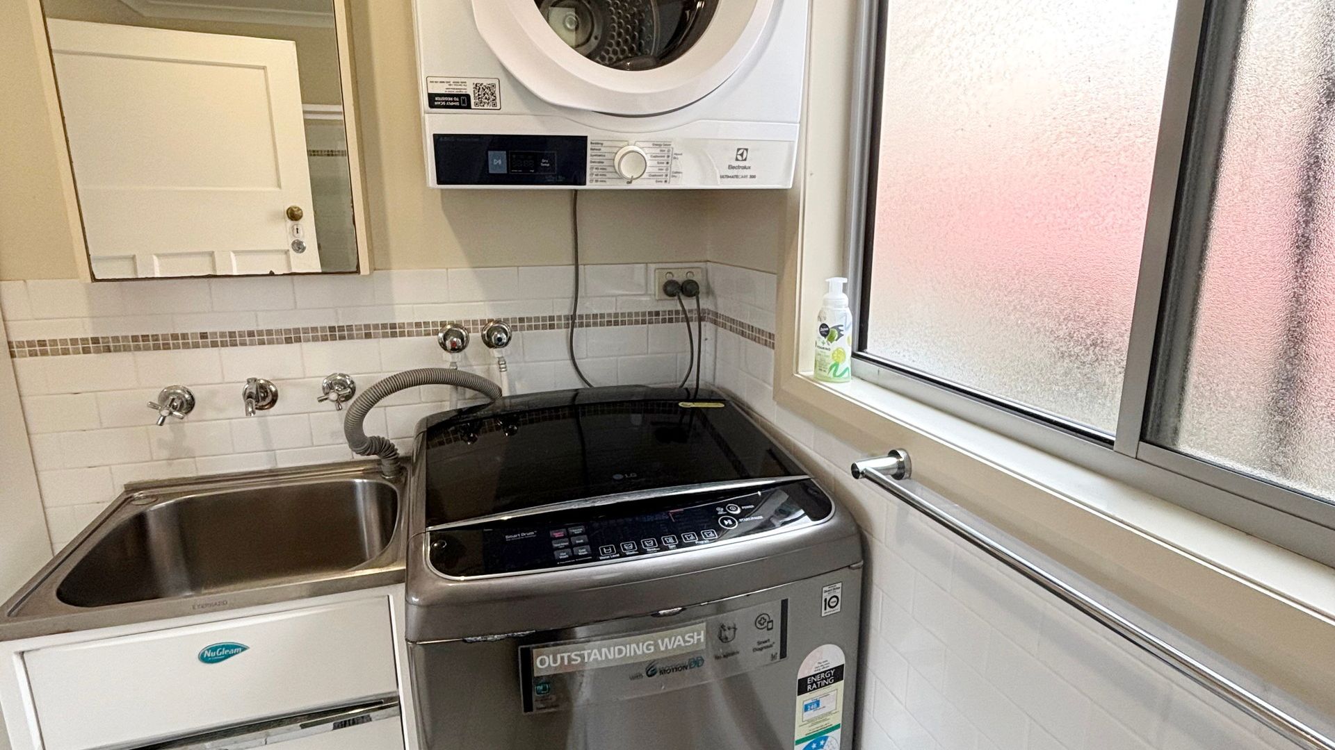 A compact kitchen with a NuClear dishwasher, a black stove, a washing machine, and a window with a view.