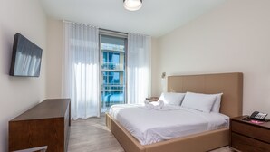 A modern hotel room with a bed, bedside table, and a desk. - Private Luxury Condos at Costa Hollywood (Hollywood)