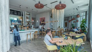 A modern restaurant interior with a bar area, wooden tables, and hanging pendant lights. - Private Luxury Condos at Costa Hollywood (Hollywood)