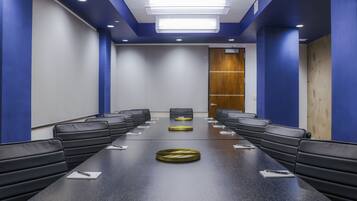 A conference room with a long table, black leather chairs, and a wooden door.