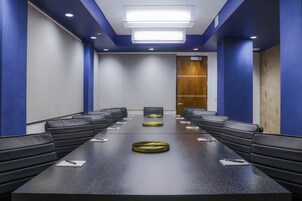 A conference room with a long table, black leather chairs, and a wooden door.