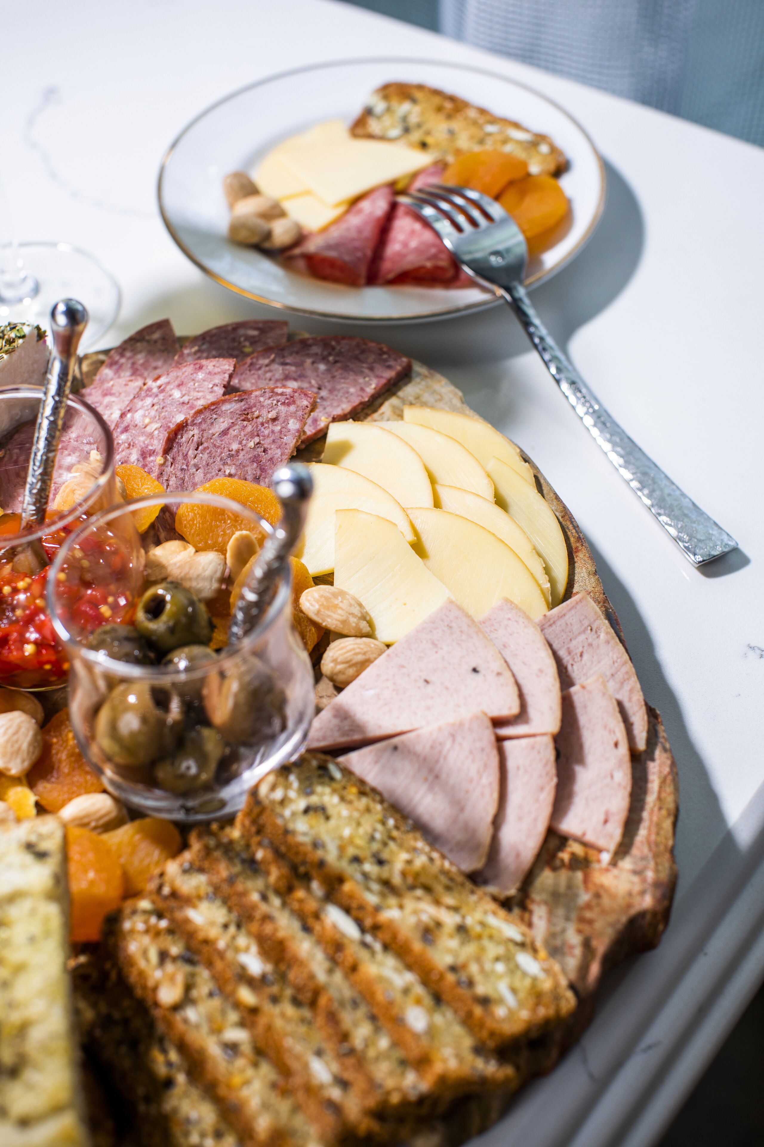 Una tabla de embutidos con diferentes carnes, quesos y frutas.