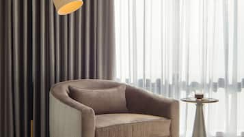 Un sillón moderno con cojín, una lámpara de pie y una mesita con una taza.