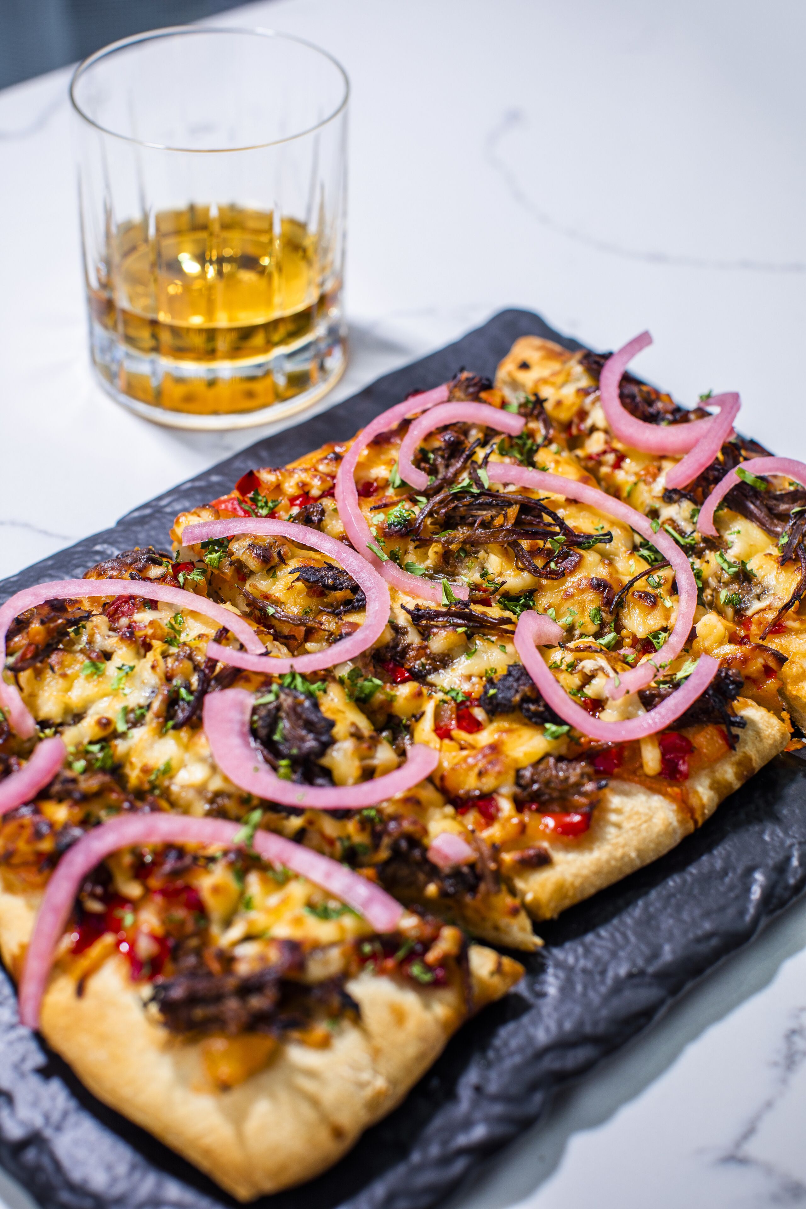 A pizza with toppings on a slate board.
